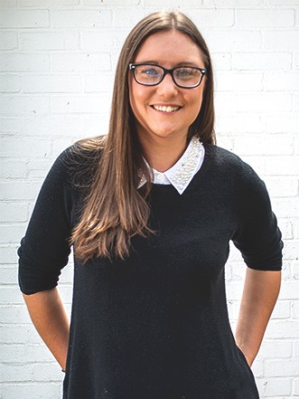 Photo of Penni Pickering, Kabo Creative's website designer, smiling in front of a white brick wall